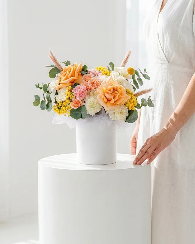 Aranjament floral pastel in cutie alba – trandafiri peach, flori delicate si accente naturale