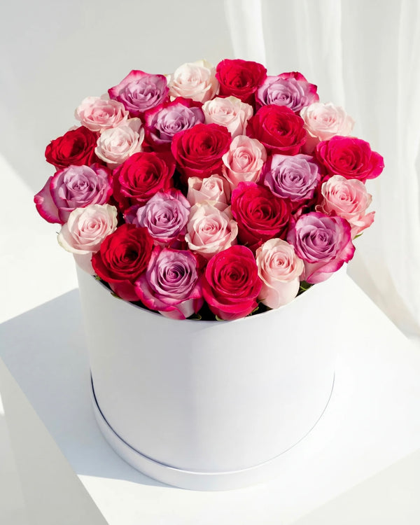 Cutie cu trandafiri mix in nuante de rosu, roz si lila – aranjament floral premium elegant