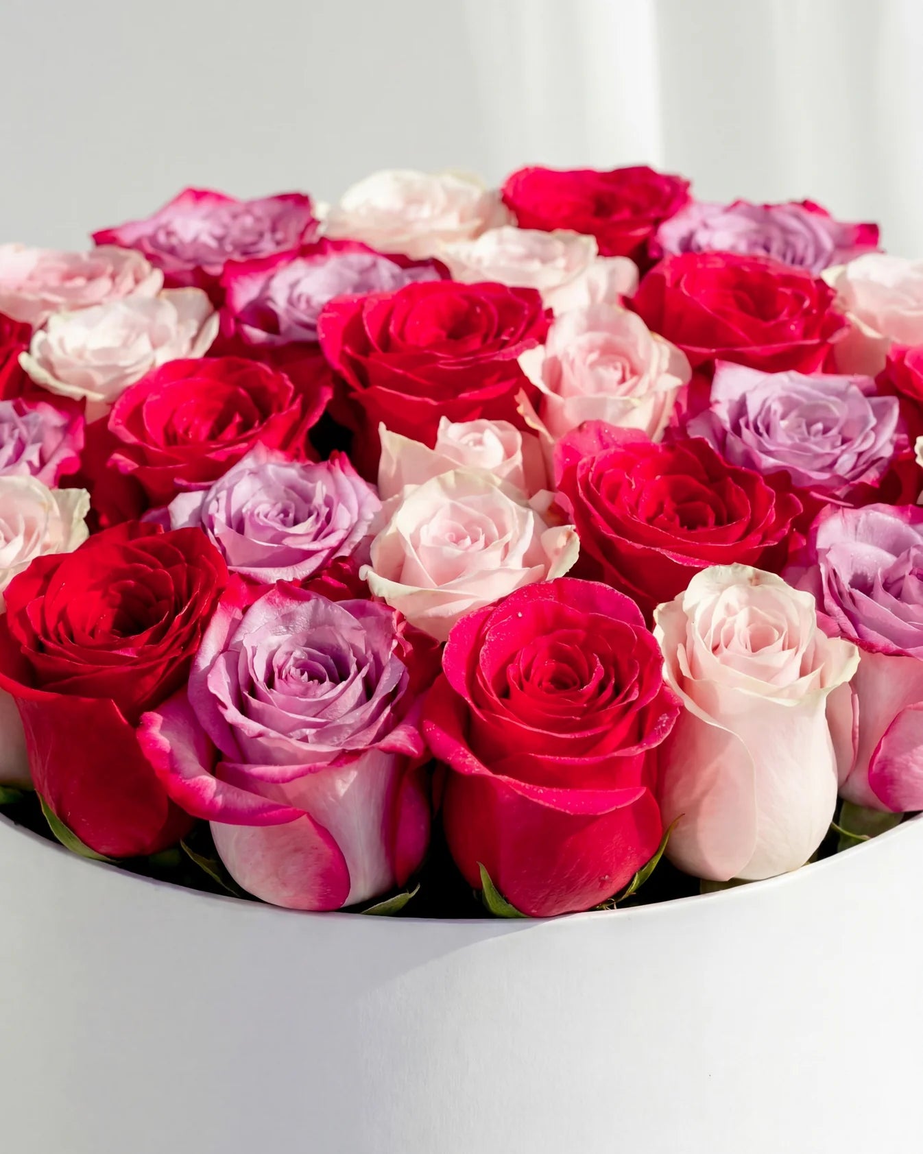 Cutie cu trandafiri mix in nuante de rosu, roz si lila – aranjament floral premium elegant